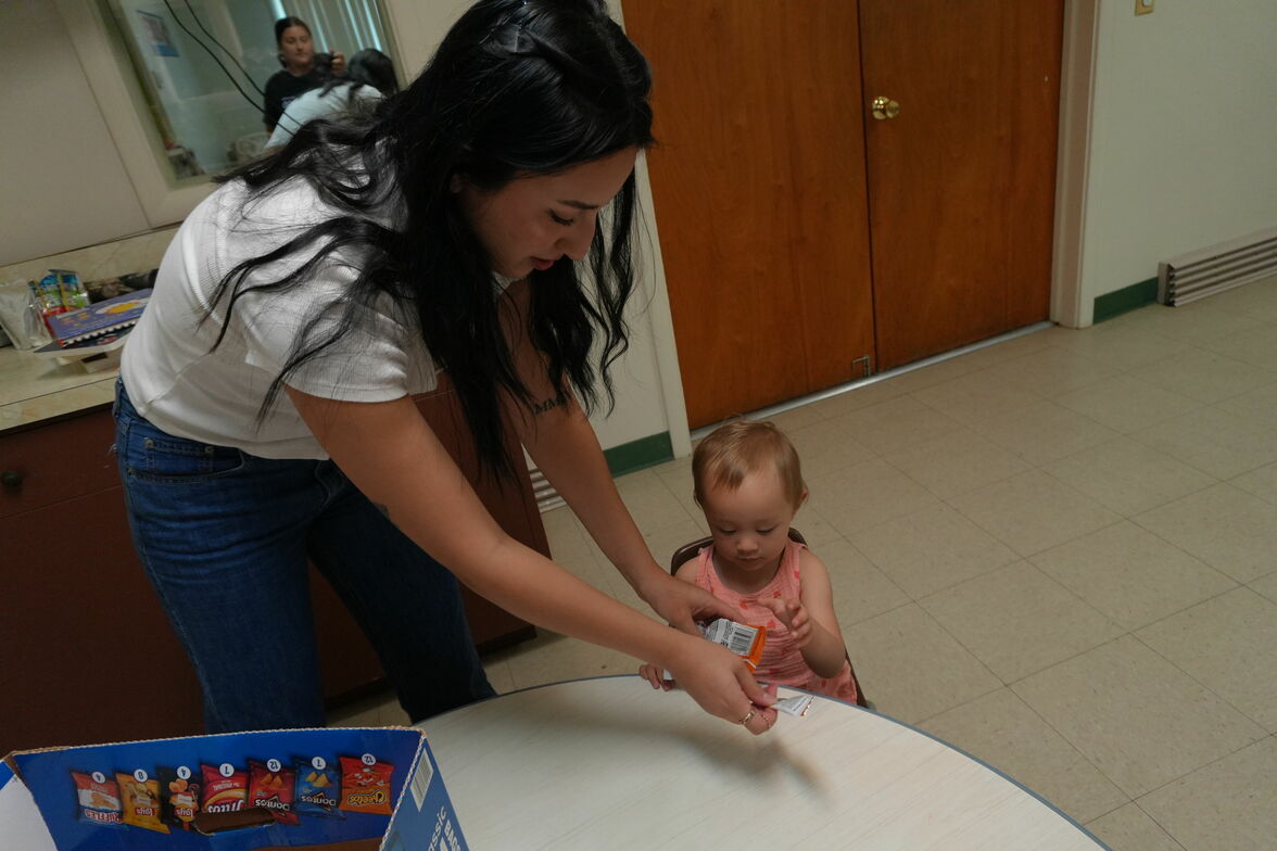 A nursery volunteer helps a child with an activity.